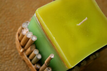 A Green And Yellow Handmade Candle Decorated With Bamboo Sticks
