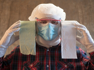 elderly man in plaid shirt protected himself from going to market. Blue mask, goggles, gloves and roll of toilet paper. pensioner was taught to make an inexpensive mask out of paper and scotch tape