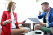 © H_Ko - Young man and woman in jackets drink coffee with documents in their hands in restaurant. Acting school teaching concept.