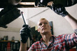 © Inuk Studio/Stocksy - Casual man repairing car from bottom
