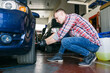 © Inuk Studio/Stocksy - Side view of man tightening lug nuts on car wheel with electric