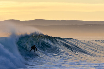 surfer riding a wave at sunrise