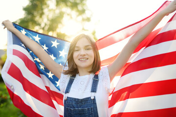 Cute girl holding American flag outdoors on beautiful summer day. Independence Day concept. Child celebrating national holiday. Remembrance day.