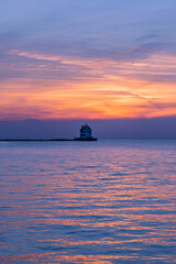 Wall Mural - Historic lighthouse in calm water of bay under beautiful sunset