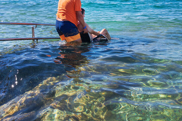 Wall Mural - Accessible beach with ramp for disabled people. Man on wheelchair going swimming.