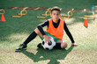 © gorynvd - Cute hispanic boy in football uniform with soccer ball after intensive training on stadium at urban park on summer day.