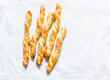 © okkijan2010 - Sesame puff pastry breadsticks on a light background, top view