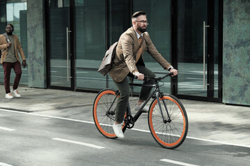 Mature businessman riding to his work by bike along the streets in the city