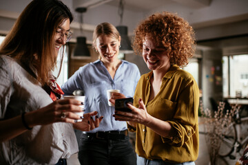 Canvas Print - Girlfriends talking and laughing in office. Beautiful women drinking coffee in the office...