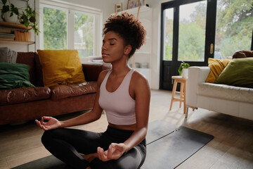 Wall Mural - Young black woman doing yoga at home in the lotus position