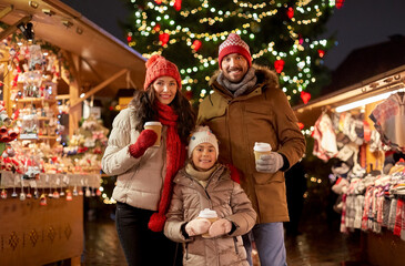 Sticker - family, winter holidays and celebration concept - happy mother, father and little daughter with takeaway drinks at christmas market on town hall square in tallinn, estonia