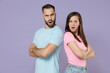 © ViDi Studio - Shocked worried irritated young couple two friends man woman in blue pink empty blank design t-shirts standing back to back holding hands crossed isolated on pastel violet background studio portrait.