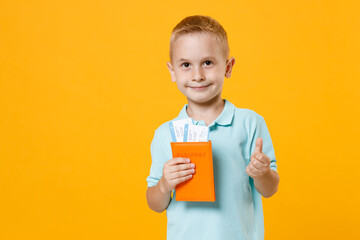 Wall Mural - Little male traveler tourist kid boy 5-6 years old in blue t-shirt polo hold passport flight tickets isolated on yellow background child studio portrait. Passenger traveling abroad on weekends getaway