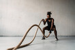 © Drobot Dean - Image of african american sportsman working out with battle ropes