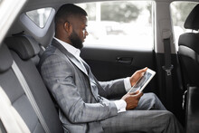 Concentrated Black Guy Manager Using Digital Tablet In Car