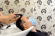 © Ana Isabel Alonso - Hombre con mascarilla a la que están lavando el pelo en una peluquería