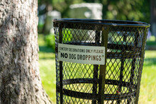 Wire Trash Can In Cemetery With Sign Stating Cemetery Decorations Only.  No Dog Droppings