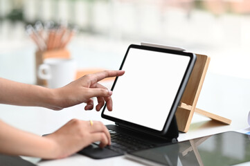 Wall Mural - Young businesswoman planing her strategy while typing on computer tablet with white screen in office.