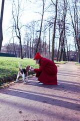 pretty young girl in redd coat playing with dog outside in green park, lifestyle people concept