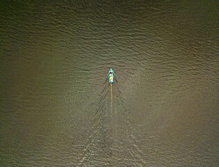 A fisherman on a boat on the river. Aerial top shot.