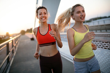 Wall Mural - Fit happy friends jogging and running together outdoor in city