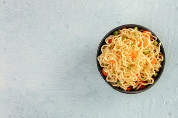 Wall Mural - Instant noodles with carrot and scallions, vegetable soba bowl, shot from above with copy space