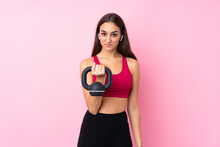 Young Sport Girl Over Isolated Pink Background Making Weightlifting With Kettlebell And Looking To The Front