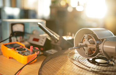 Wall Mural - Close-up of motor from home cooling fan lies on a table in workshop