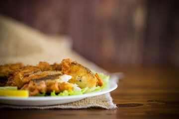 Wall Mural - fried hake fish in batter with lettuce and lemon in a plate