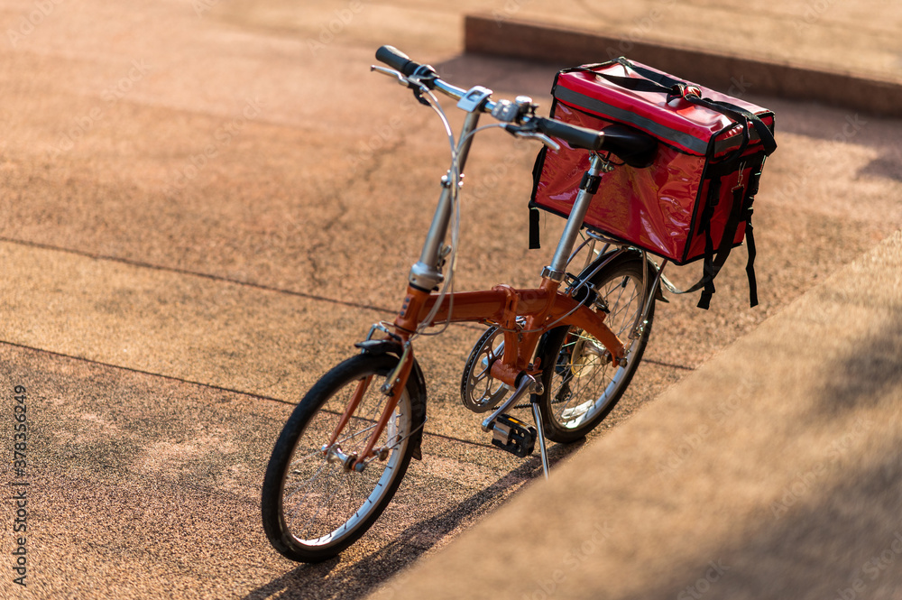 A red bag placed on a bicycle preparing to deliver parcels to customers - obrazy, fototapety, plakaty 