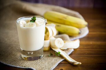 Wall Mural - tasty homemade yogurt with bananas in a glass on a wooden table