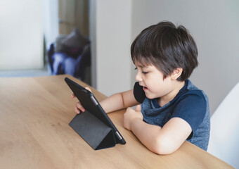 Kid using tablet  studying homework, Child using digital tablet for his online lesson at home during quarantine, Home schooling, Social Distancing and E-learning online education concept
