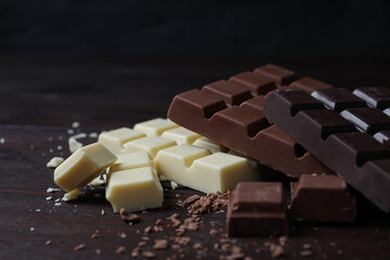 Different tasty chocolate bars on wooden table