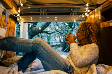 Relaxed adult woman inside a vintage wooden van enjoy the natoure outdoor and the travel lifestyle - tourist and vehicle camping life with forest view outside - wanderlust and van life modern concept