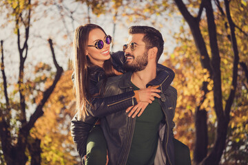 Canvas Print - Photo of positive couple guy hug piggyback beloved girlfriend in september orange town park wear jacket sunglass