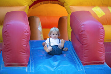 Children, boys, playing jumping on colorful trampoline