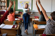 © Wavebreak Media - Female teacher pointing towards kids raising their hands in class at school