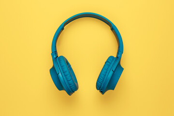 Blue headphone on yellow background. Music concept.