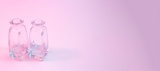 Wall Mural - concept with two shaped square-bottom crystal clear clean empty glasss bottles standing on colorful 
