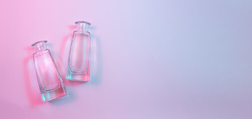 Wall Mural - concept with two shaped square-bottom crystal clear clean empty glasss bottles laying on colorful ba