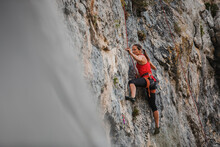 Confident Female Rock Climber Climbing Mountain