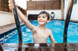 © JOSEP M ROVIROSA/Westend61 - Smiling boy holding ladder in swimming pool