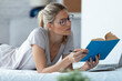 © JOSEP SURIA/Westend61 - Blond woman reading a book lying in bed