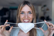 © JOSEP SURIA/Westend61 - Portrait of smiling young woman putting on protective mask