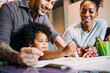 © Eugenio Marongiu/Westend61 - Smiling parents looking at baby daughter drawing on paper at home