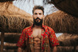 © Miguel Frias/Westend61 - Attractive bearded man with colorful shirt standing between beach umbrellas