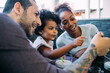 © Eugenio Marongiu/Westend61 - Close-up of smiling family looking at smart phone while sitting in dining room