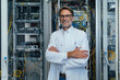 © Mareen Fischinger/Westend61 - Smiling mature man with arms crossed standing in server room