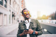 © Oscar Carrascosa/Westend61 - Cheerful man wearing sunglasses using smart phone while standing in city