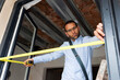 © VALENTINA BARRETO STUDIO/Westend61 - Architect using tape measure on window frame in a house under construction